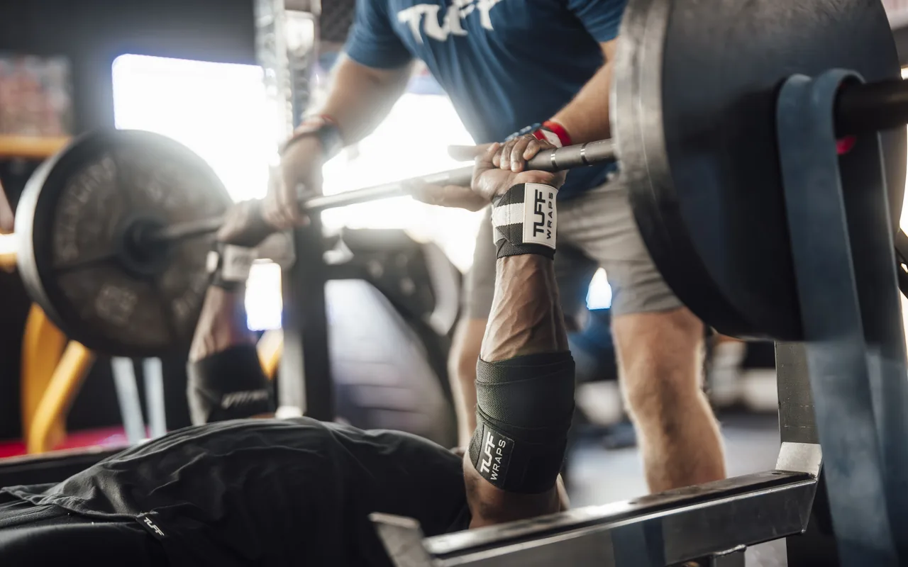 A lifter bench pressing while wearing TuffWraps wrist wraps