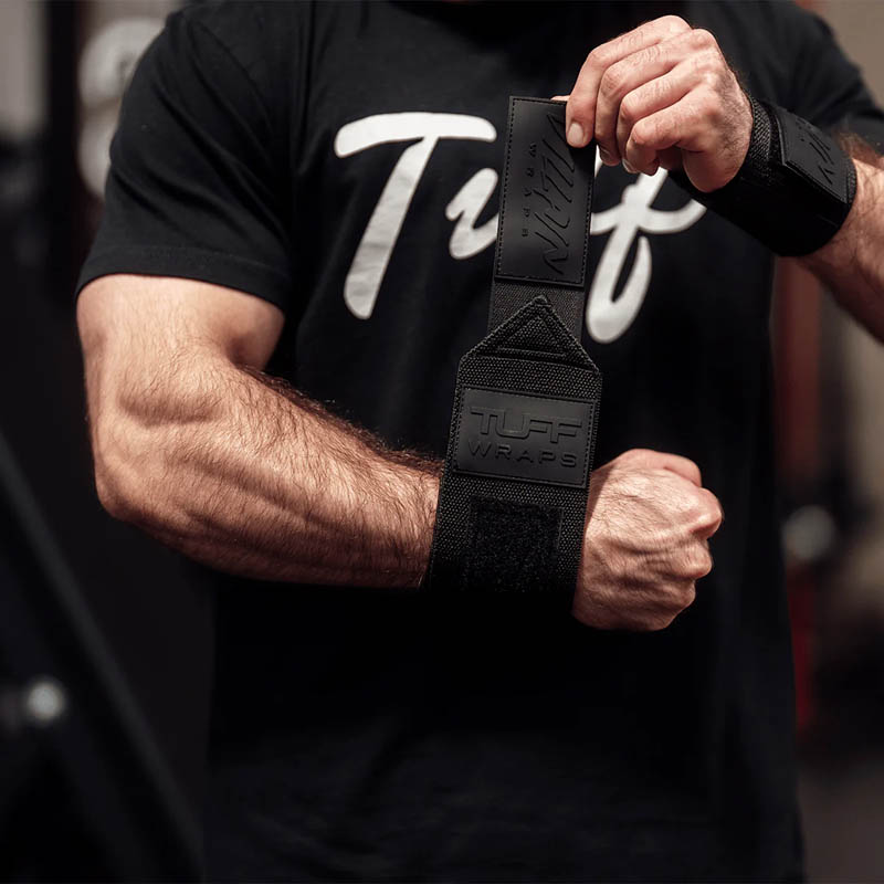 A lifter tightening a Blackout Villain wrist wrap over the wrist joint